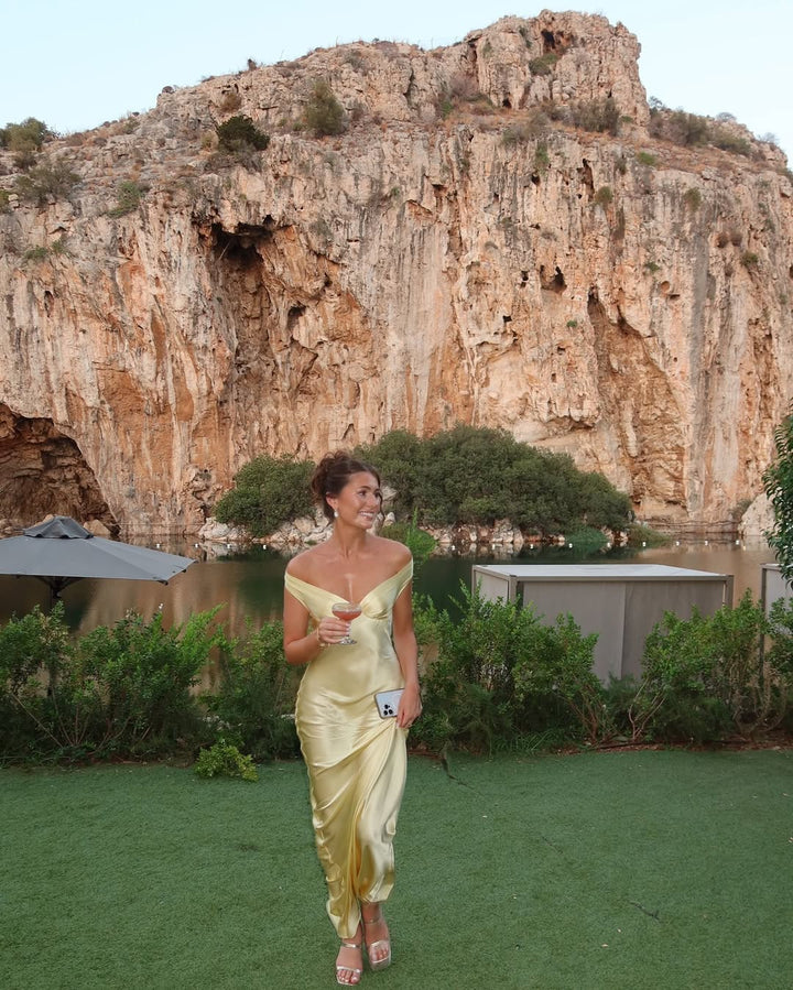 Luxurious gold off-shoulder maxi dress, an elegant evening gown for women attending weddings or galas.