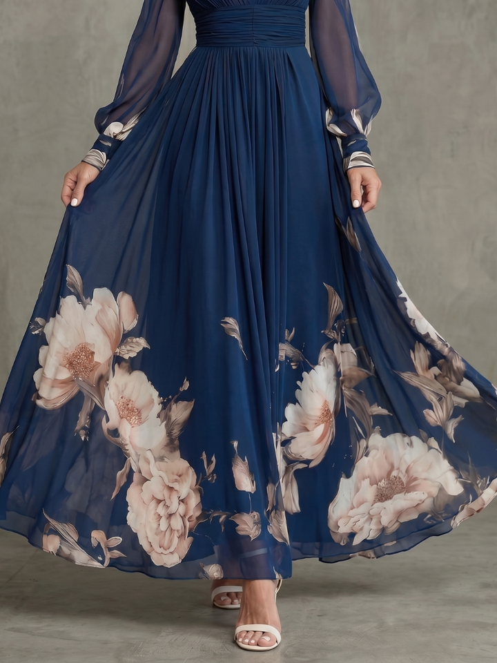 Woman models an elegant navy V-neck pleated maxi dress with sheer sleeves, showing its flowy design and sophistication.