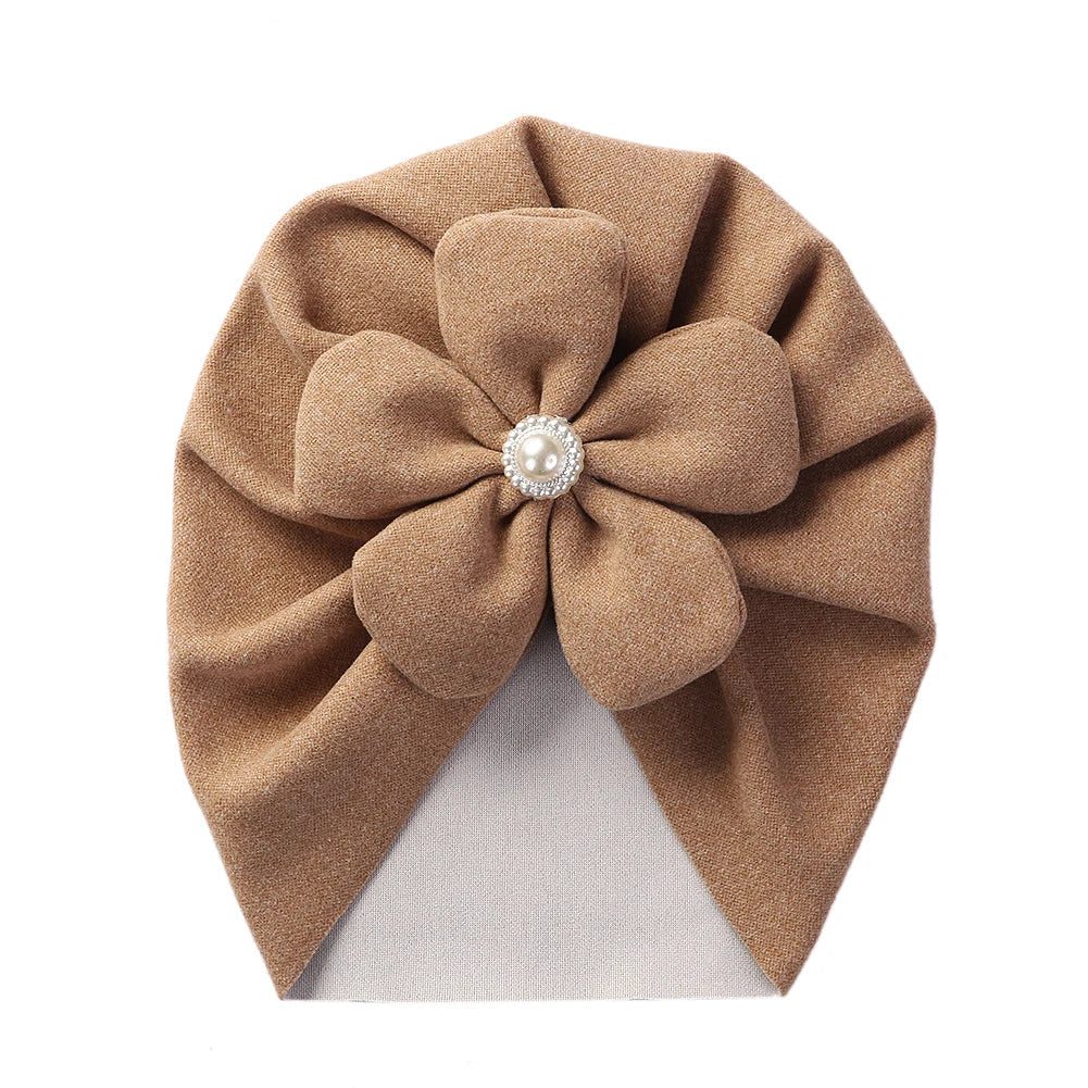 Close-up of the textured fabric and pearl details on an elegant baby turban hat.