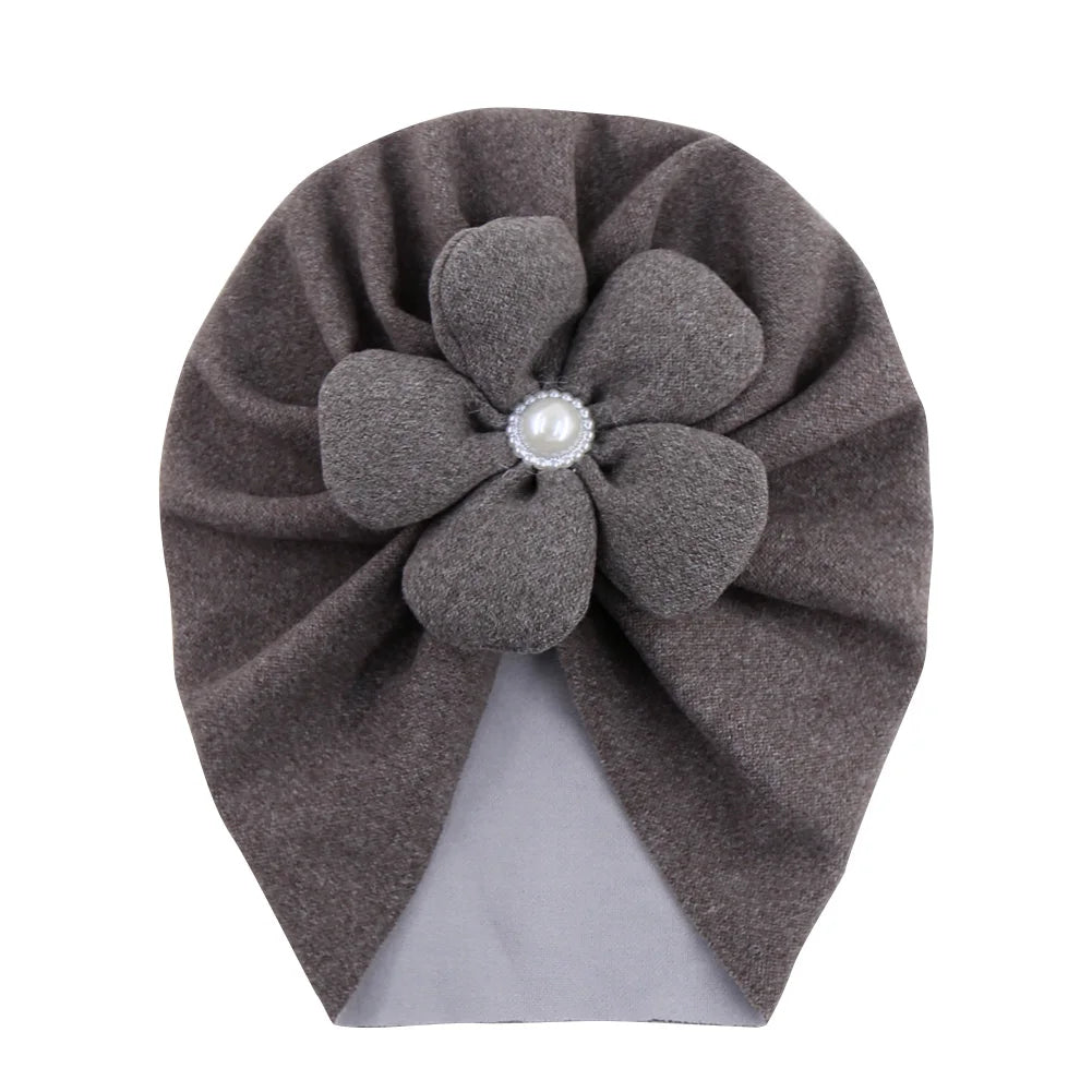 Baby wearing a delicate pearl-embellished turban hat, looking adorable and comfortable.