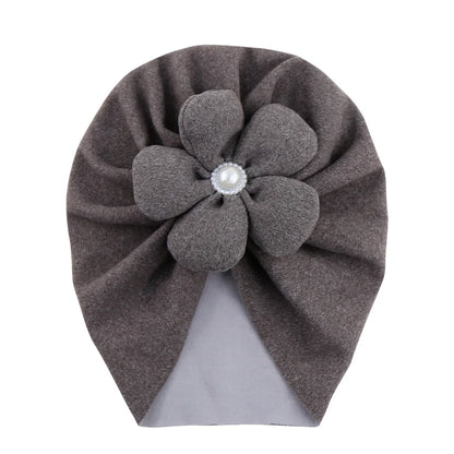Baby wearing a delicate pearl-embellished turban hat, looking adorable and comfortable.