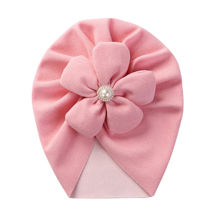 Soft green baby turban hat with an intricate pearl flower, a unique newborn headwear choice.