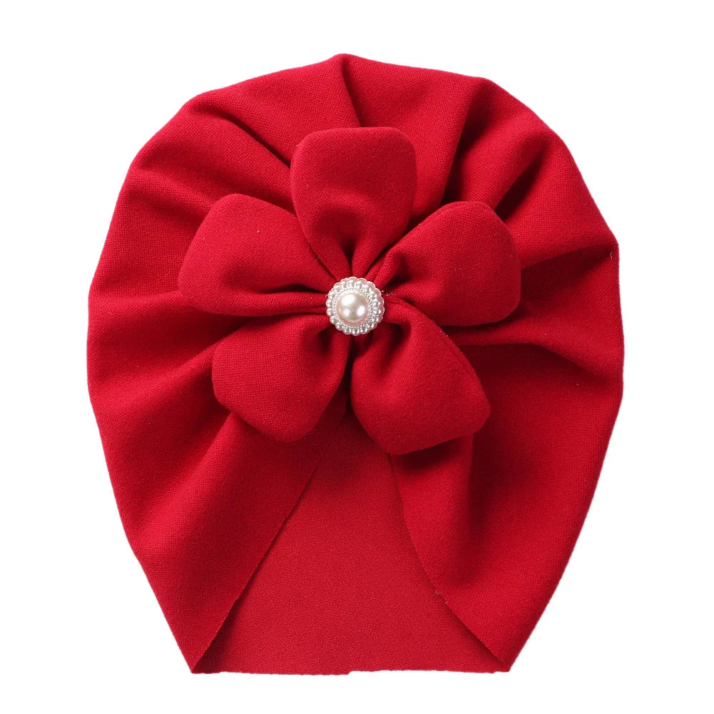 Elegant baby accessory: purple turban hat with a cluster of pearls forming a flower.