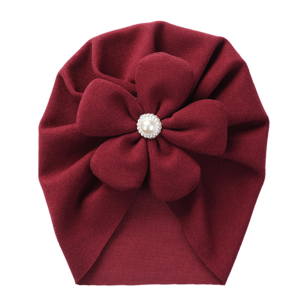 Faux cashmere baby turban hat in beige, decorated with a pretty pearl and petal motif.