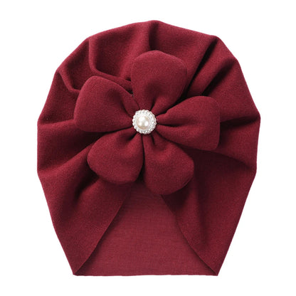 Faux cashmere baby turban hat in beige, decorated with a pretty pearl and petal motif.