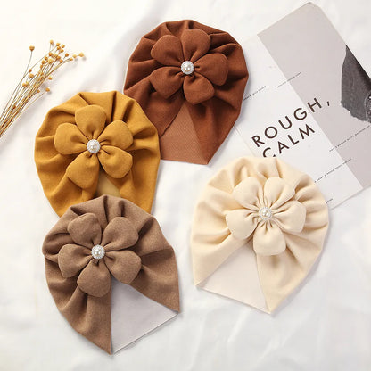 White baby turban hat with delicate pearl and floral embellishment, ideal for infants.