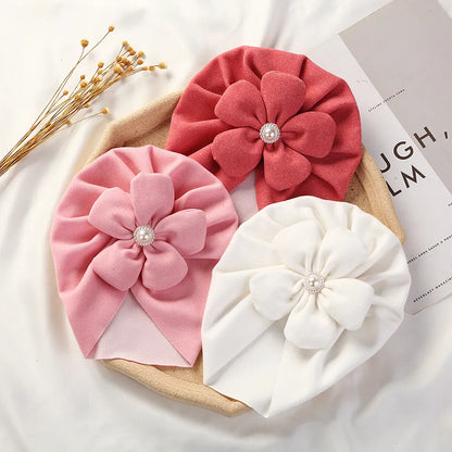 Unisex baby pearl turban hat in cream, a cozy and stylish newborn headwear accessory.