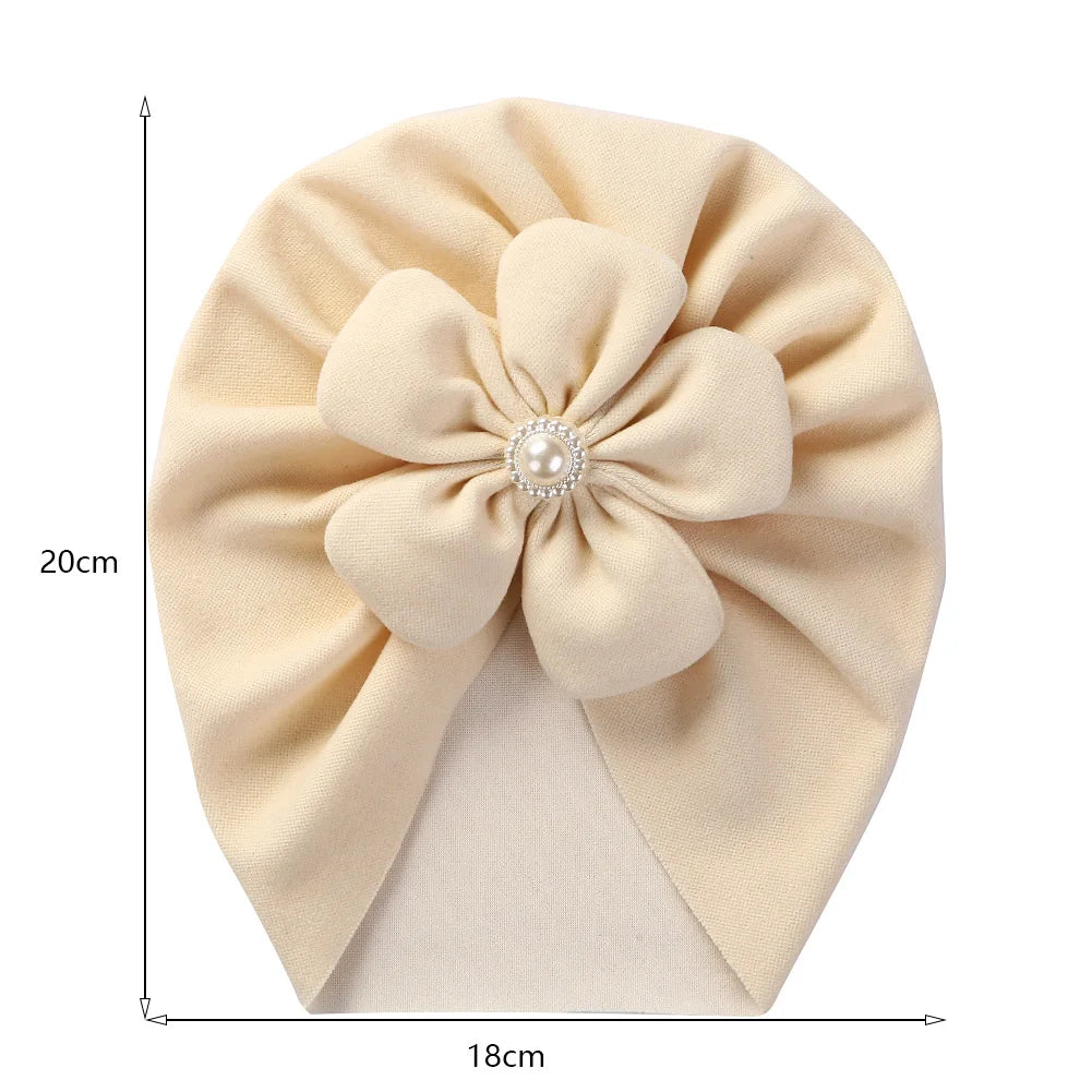Close-up of a baby turban hat featuring a beautiful pearl flower detail on soft fabric.