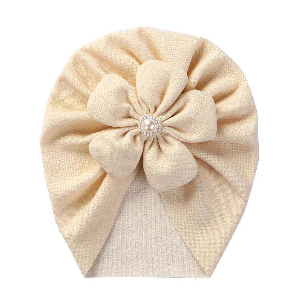 Baby fashion turban hat in a vibrant fuchsia, featuring a dainty pearl and floral design.