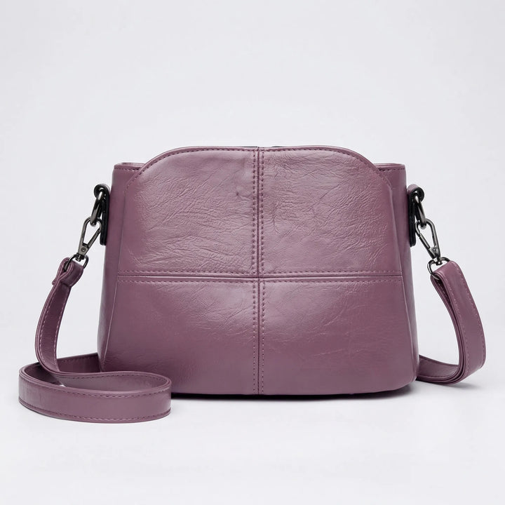 Chic purple women's mini shoulder bag with unique stitched panel detailing, a trendy and compact handbag.