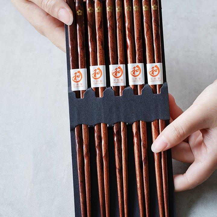 Five pairs of elegant wooden chopsticks with golden cherry blossom design, presented in a gift-ready Japanese tableware set.