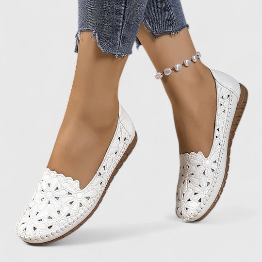 Stylish women's ballet flats in white with delicate perforated floral pattern and elegant scalloped edges.