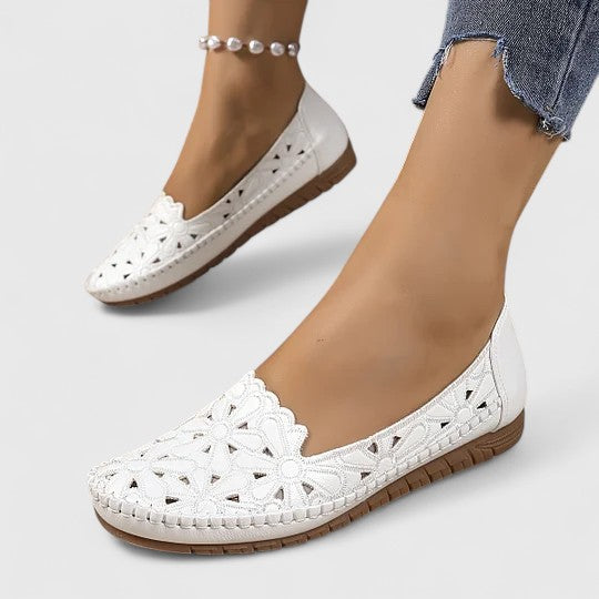 Side view of women's slip-on ballet flats in white, featuring feminine floral perforations and round toe.