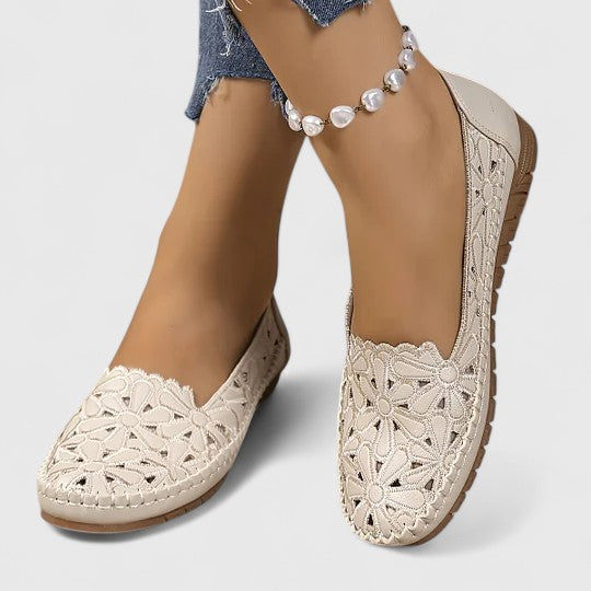 White women's ballet flats with perforated floral design, a stylish and comfortable slip-on shoe choice.