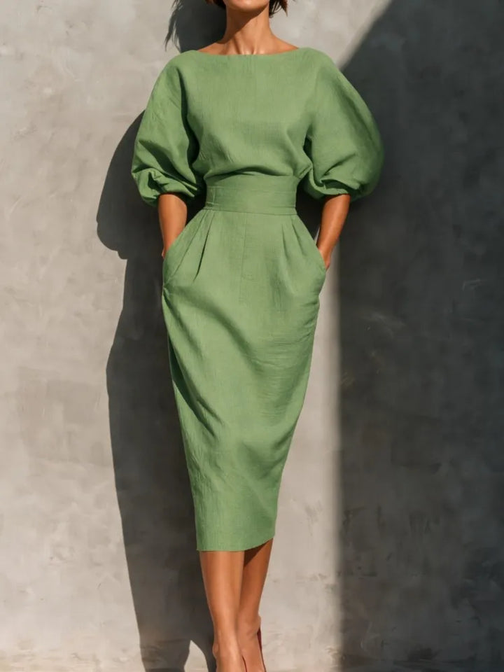 Chic women's midi dress featuring elegant pleats, lantern sleeves, & a cinched waist for spring/summer.