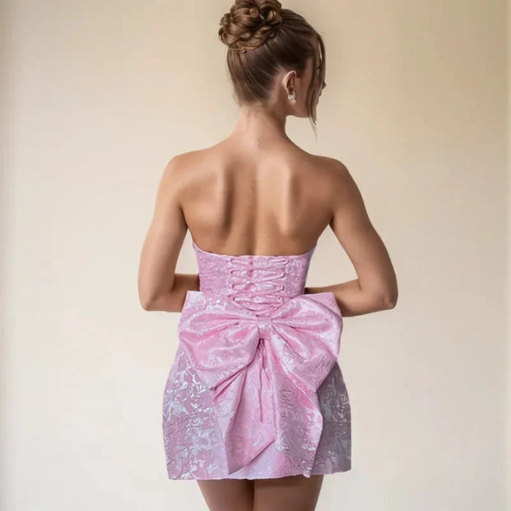 Fashionable women's strapless mini dress, featuring a prominent bow back detail, for a stylish look.
