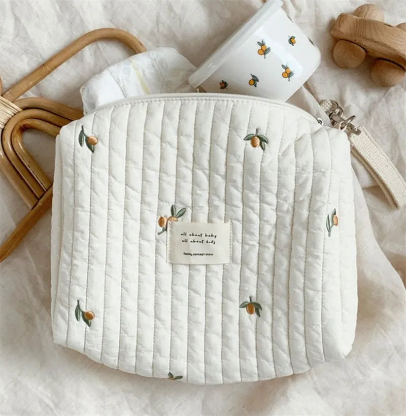 Diaper caddy bag with delicate embroidery, designed for easy attachment to baby transport