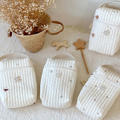 Embroidered cotton stroller wet bag hanging on handle, storing baby essentials easily.
