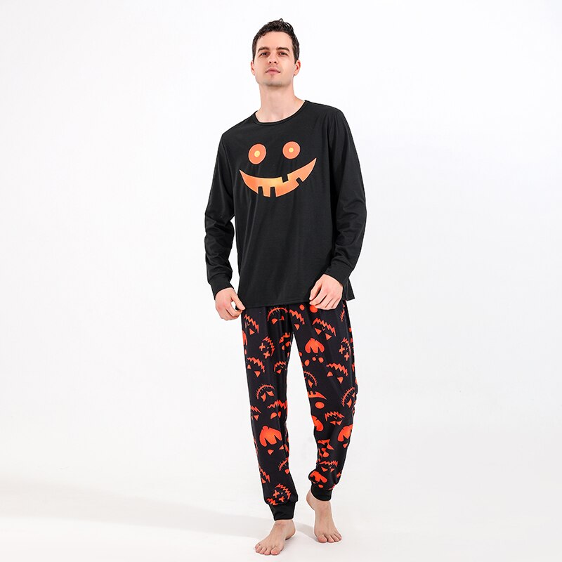 Adult and child hands holding, showing off matching Halloween themed pajama fabric, soft stretch material.