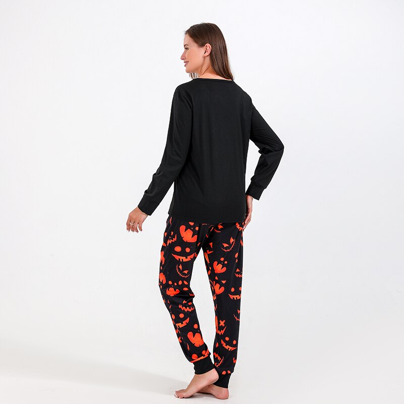 Full shot of a family (dad, mom, child) wearing coordinating Halloween bat print pajamas, cozy home wear.