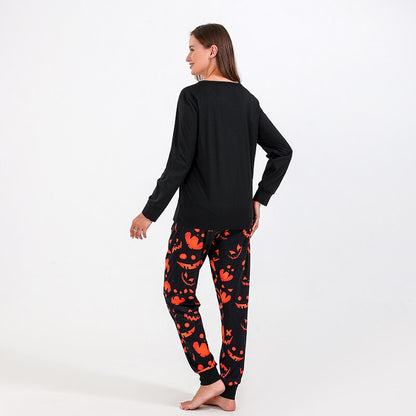 Full shot of a family (dad, mom, child) wearing coordinating Halloween bat print pajamas, cozy home wear.