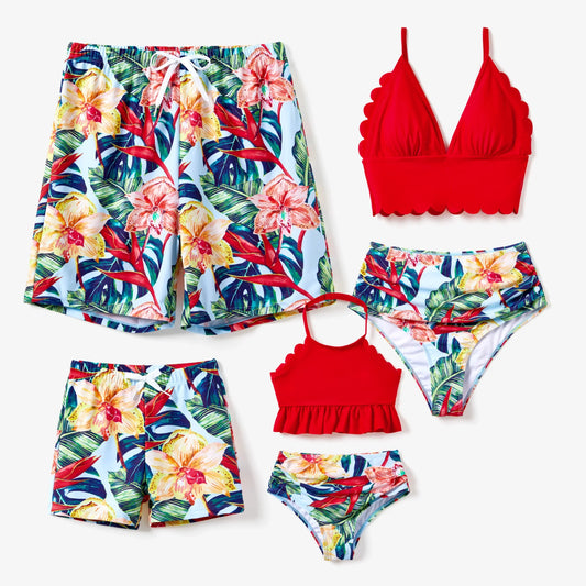 Family in matching pink floral swimsuits & cover-ups on beach, vacation attire.