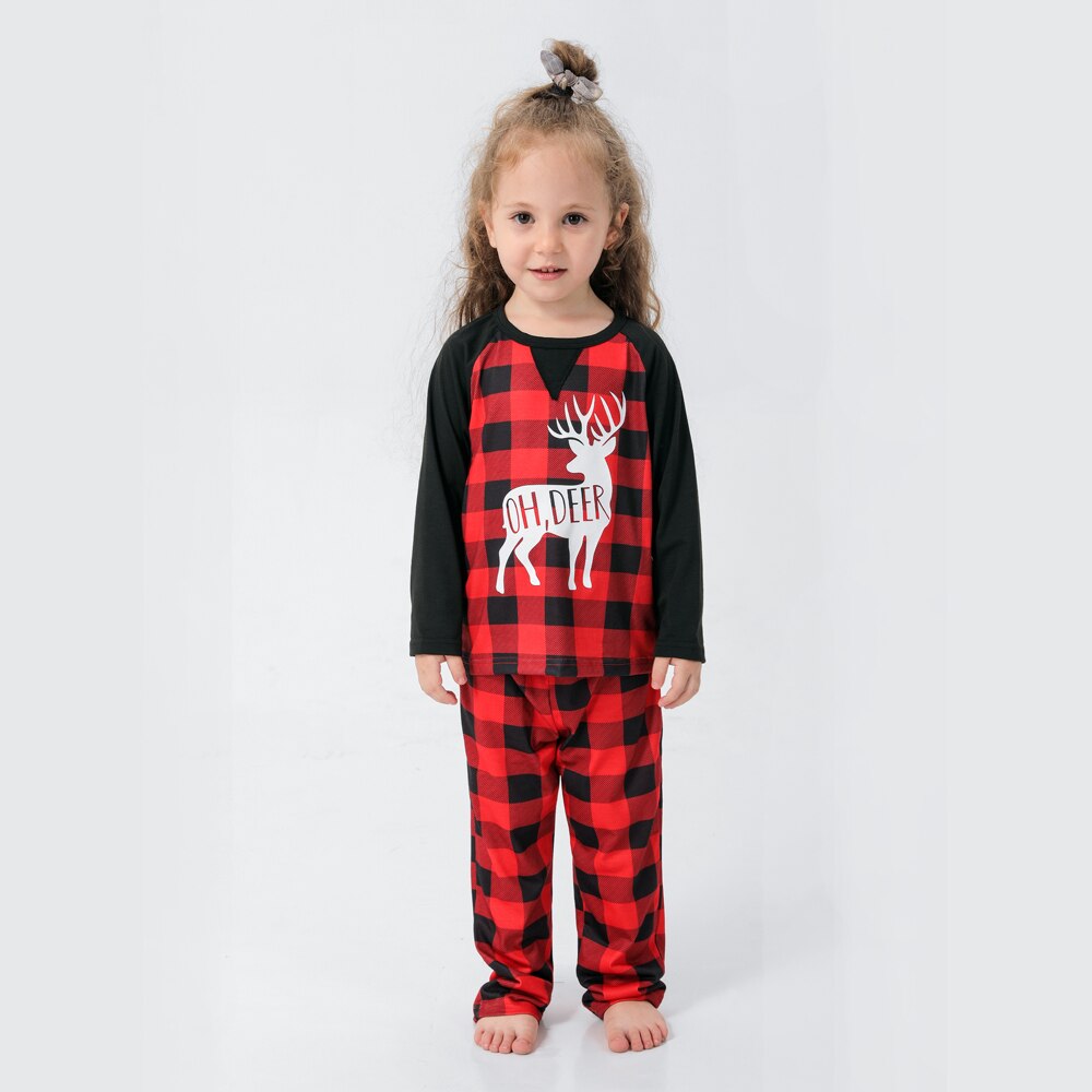Family walking in snow wearing matching plaid reindeer Christmas pajamas, festive and warm