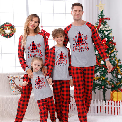 Close-up of a baby in a red plaid Christmas sleepsuit, 'My First Christmas' embroidered; soft cotton blend.