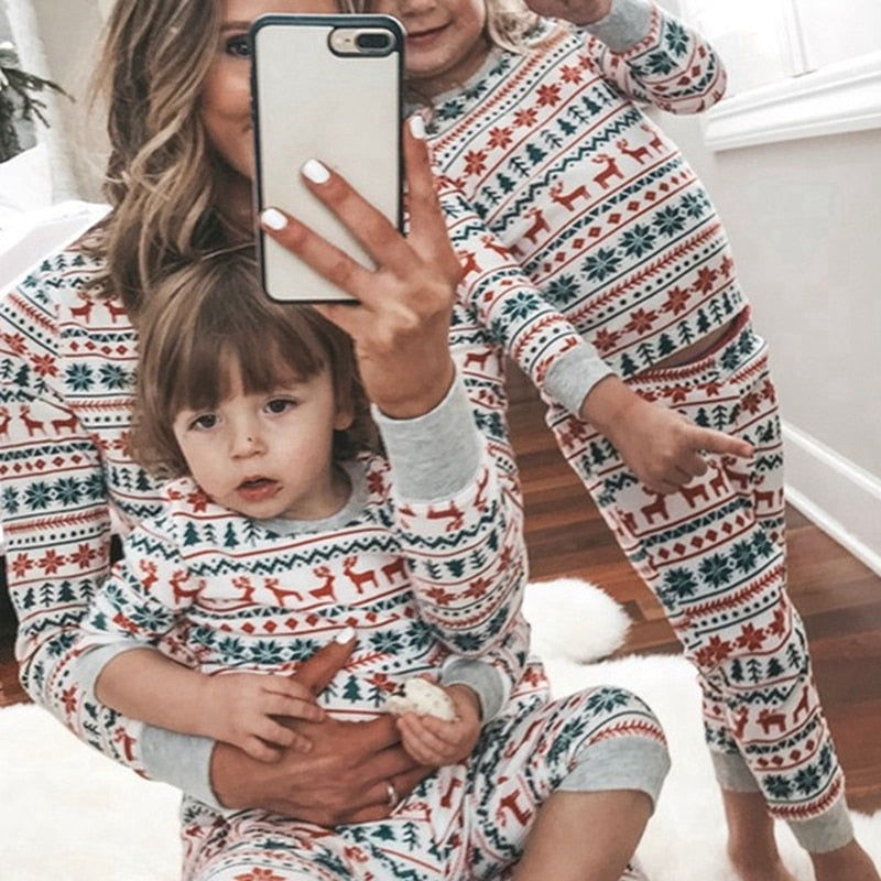 Father and son laughing in comfortable striped Christmas pajamas, drinking cocoa.