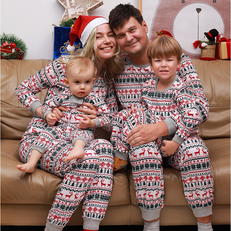 Full family shot wearing coordinated green and red Christmas sleepwear, on a couch.