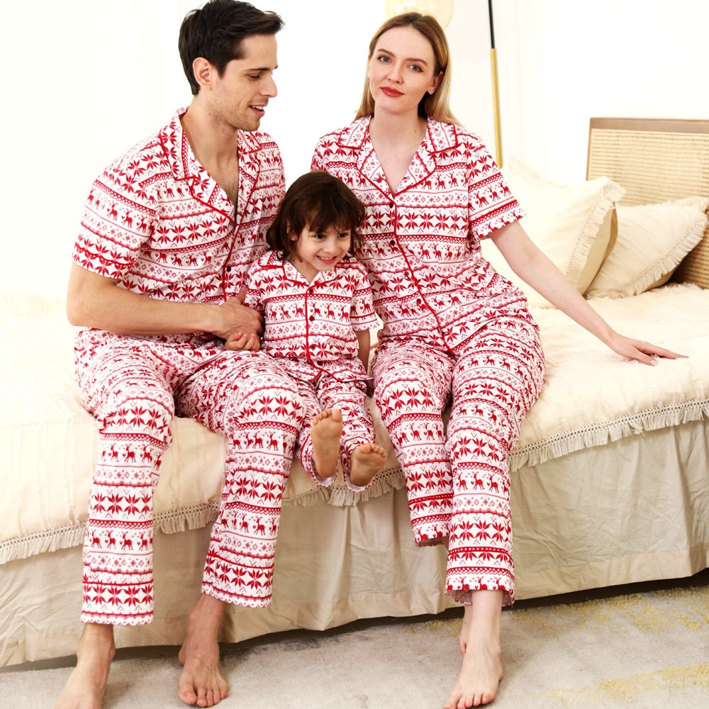 Family in matching red short-sleeve polyester Christmas pajamas laughing together at home