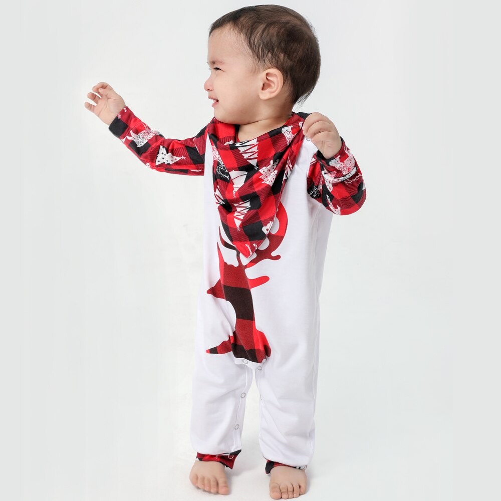 Adorable toddler in red plaid holiday pajamas on a rug, part of a family Christmas pajama set.