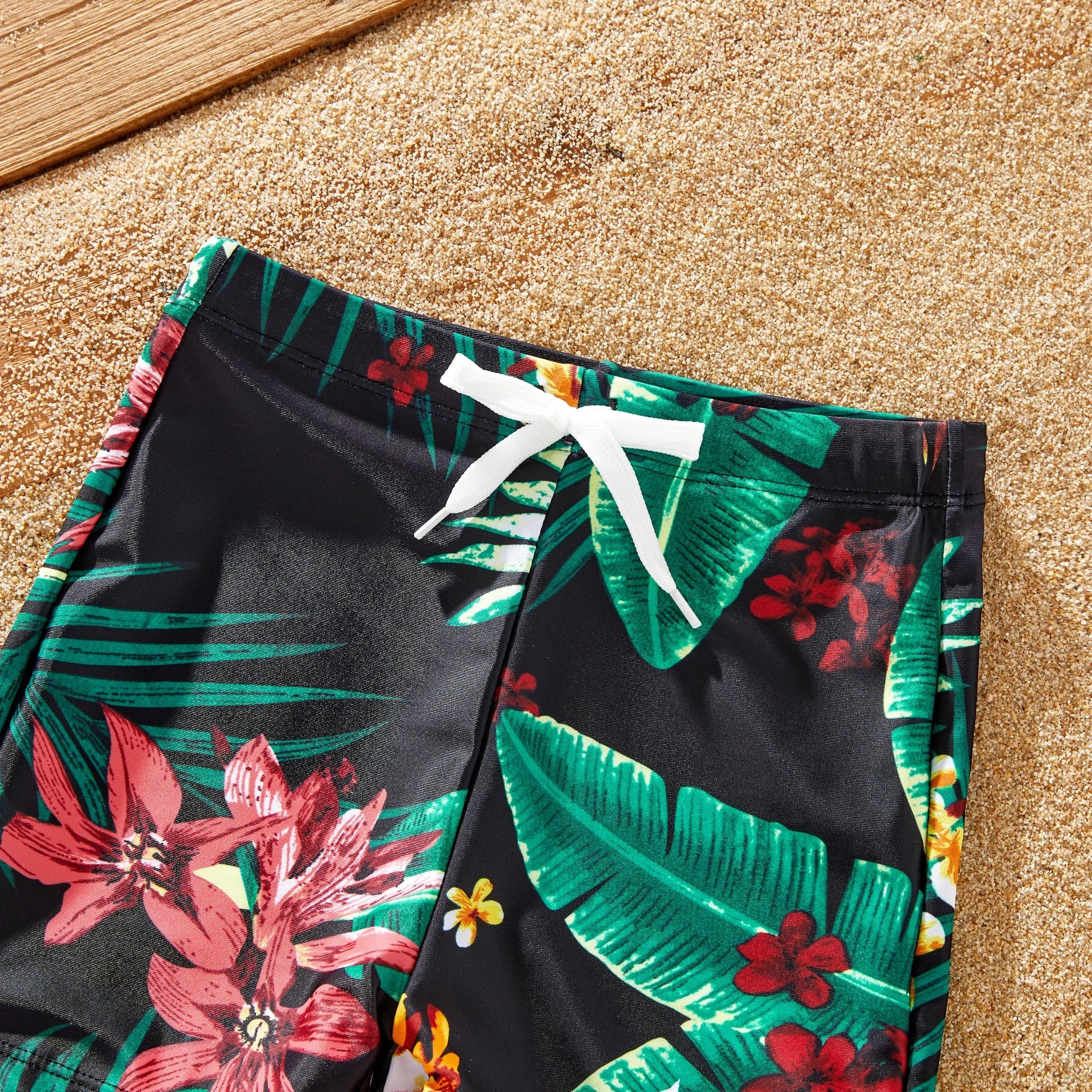 Family matching swimsuits and floral drawstring trunks on a sunny beach vacation.