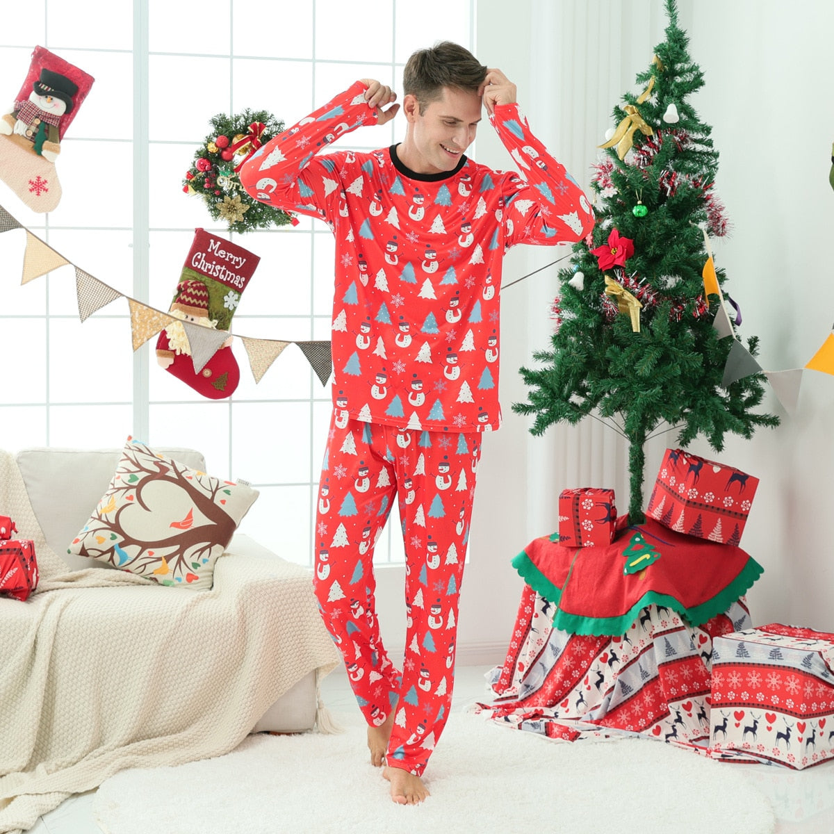Adult holding a child, both dressed in matching red Christmas snowman pajamas, warm winter apparel