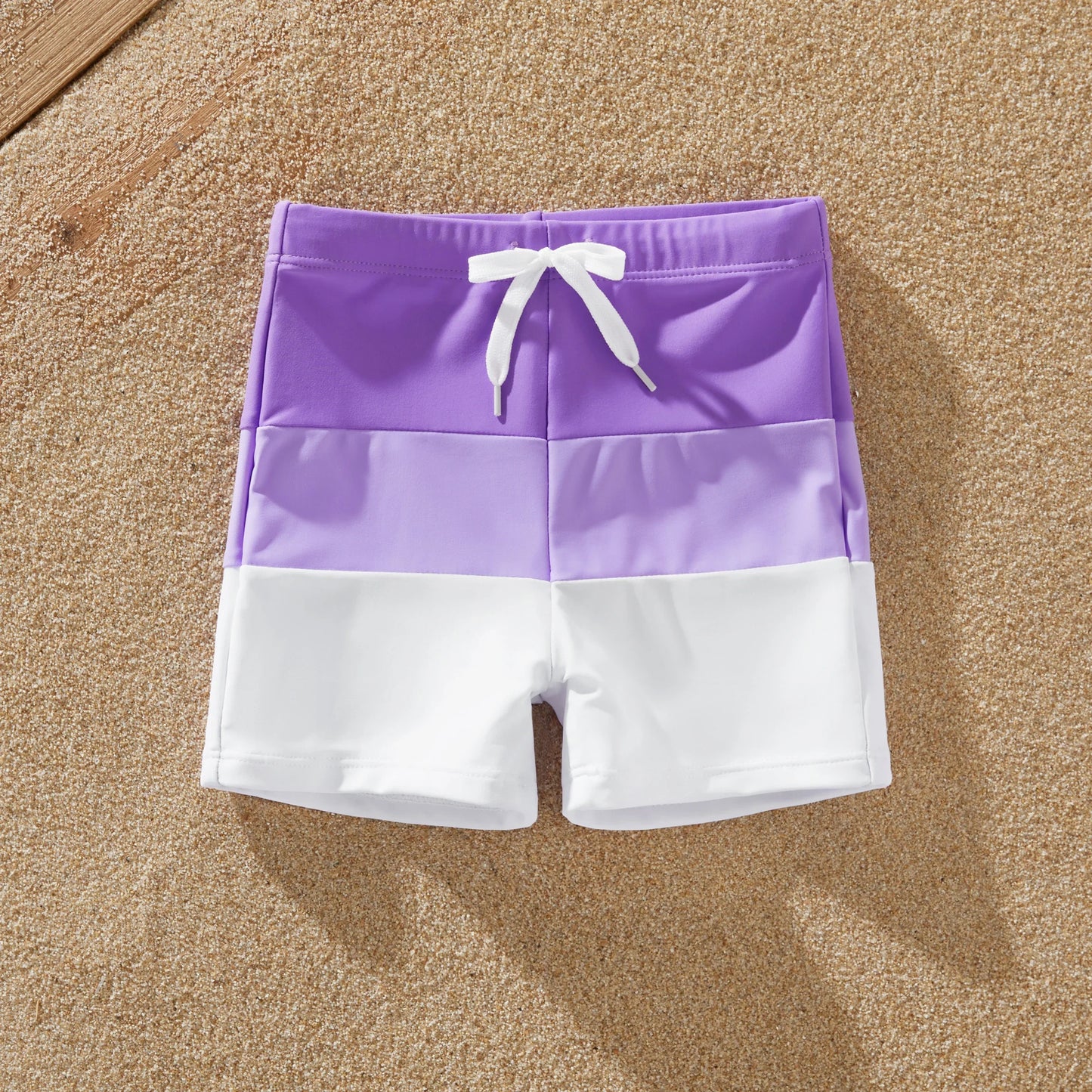 Dad and son wearing matching color-block swim trunks, perfect for summer
