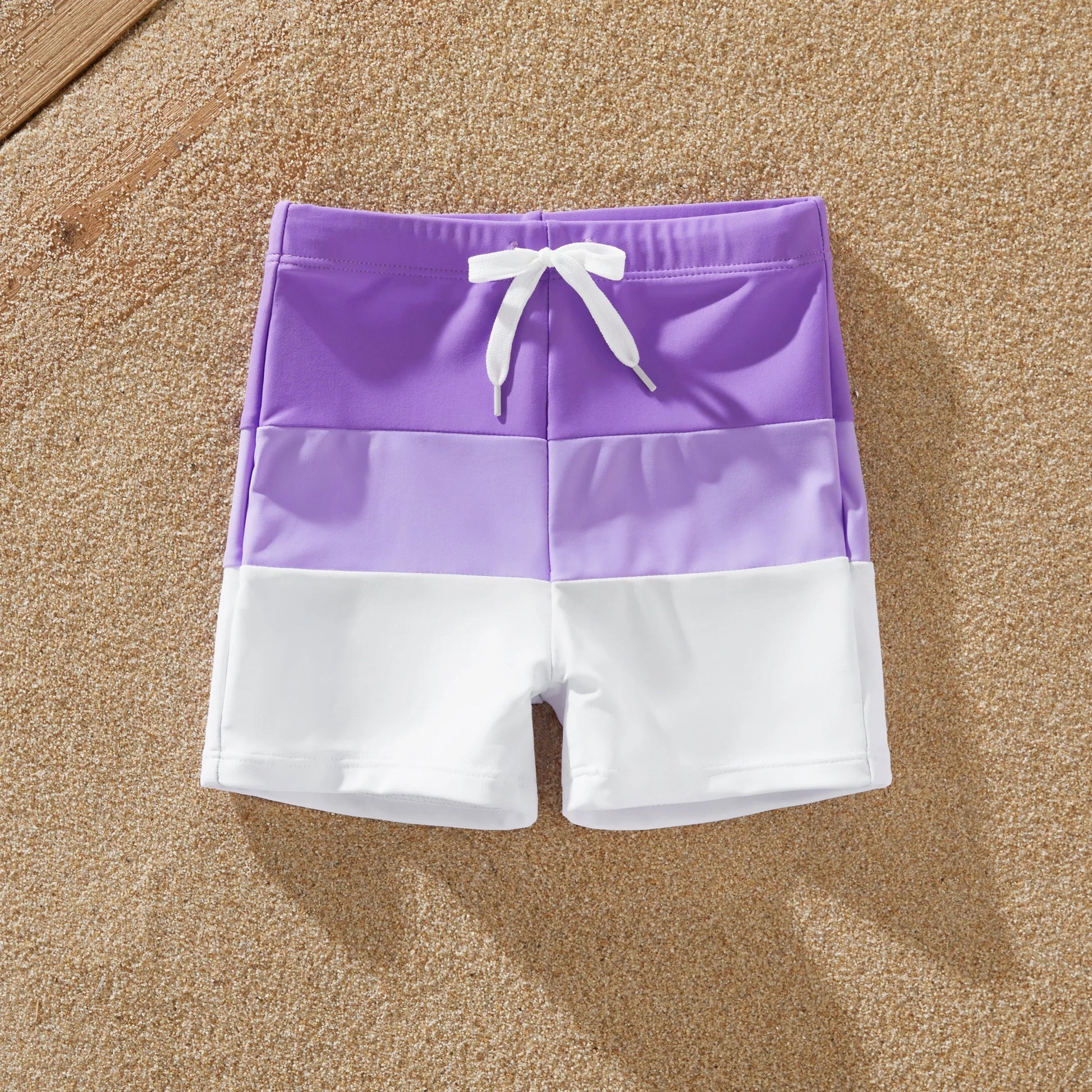 Dad and son wearing matching color-block swim trunks, perfect for summer