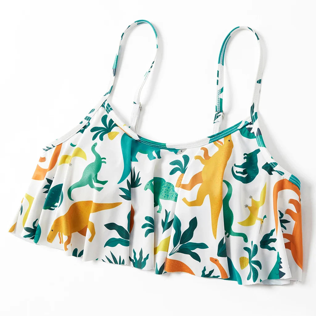 Man in blue dinosaur print board shorts, standing by the pool, ready for swimming.