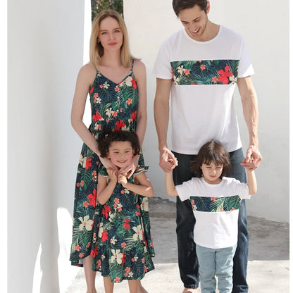 Family matching floral print outfits: women's dress, men's shirt, kid's romper on a beach