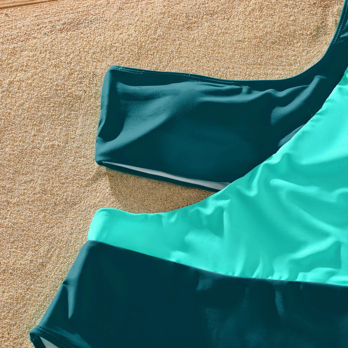 Green one-shoulder swimsuit and striped trunks for family, ideal for poolside fun