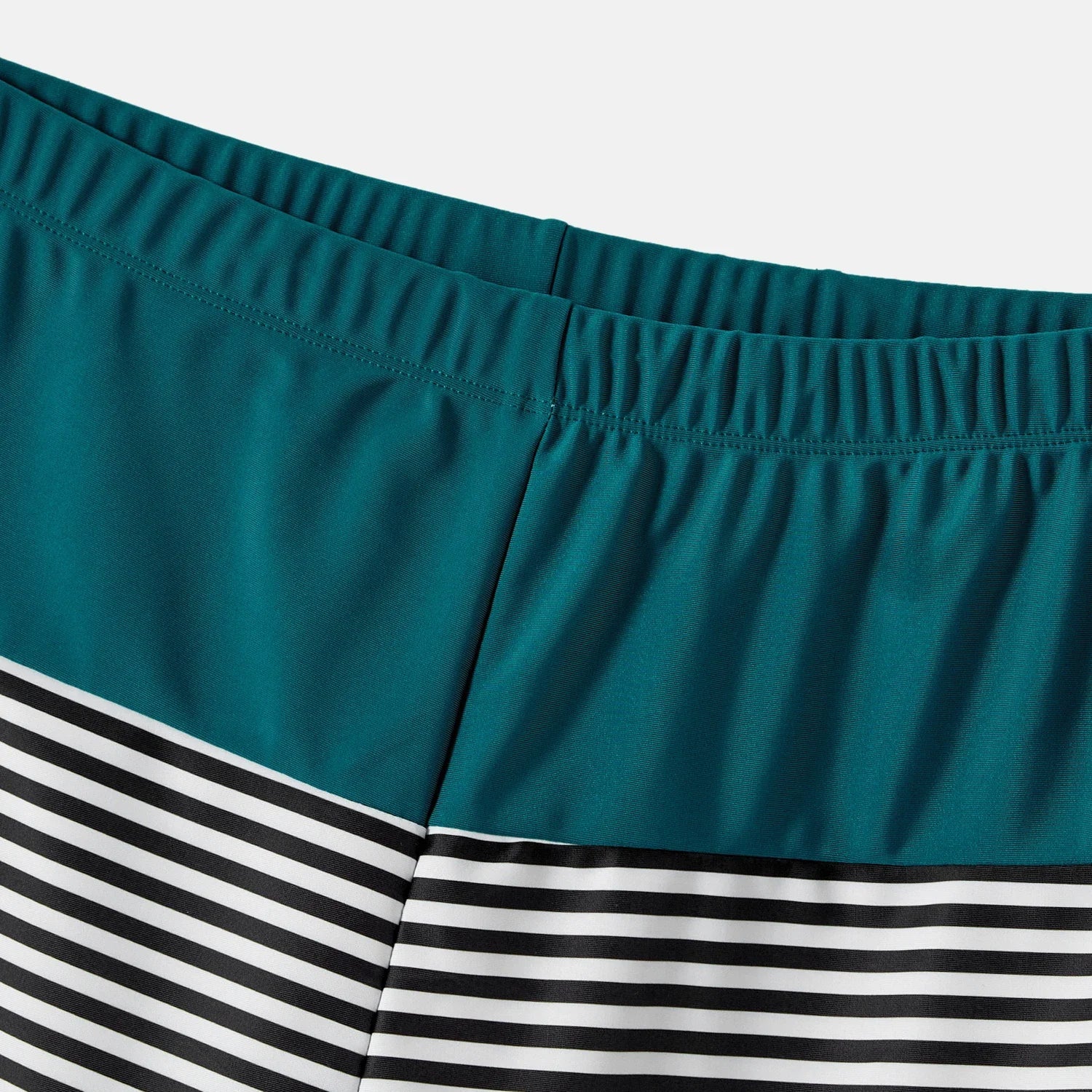 Family smiling and relaxing by the ocean in their matching green swimwear
