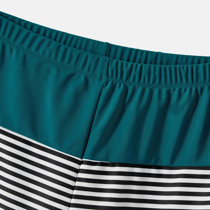 Family smiling and relaxing by the ocean in their matching green swimwear