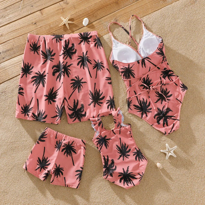 Family posing in pink coconut tree print swimsuits, enjoying the summer