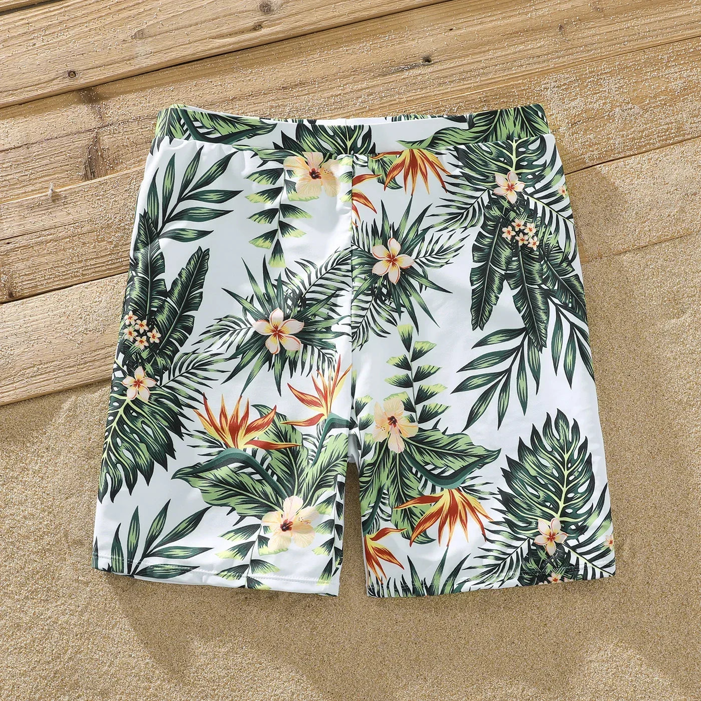Family on a sandy beach, all wearing their matching plant print swimsuits, summer vacation goals