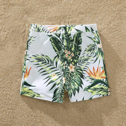 Woman in a plant print ruffle swimsuit, holding a tropical drink, perfect for beach relaxation