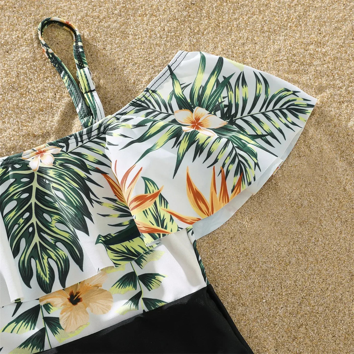 Family posing happily in matching plant print tropical swimsuits, ideal for beach vacation photos