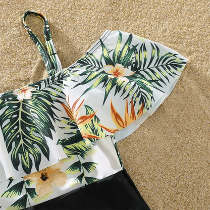 Family posing happily in matching plant print tropical swimsuits, ideal for beach vacation photos