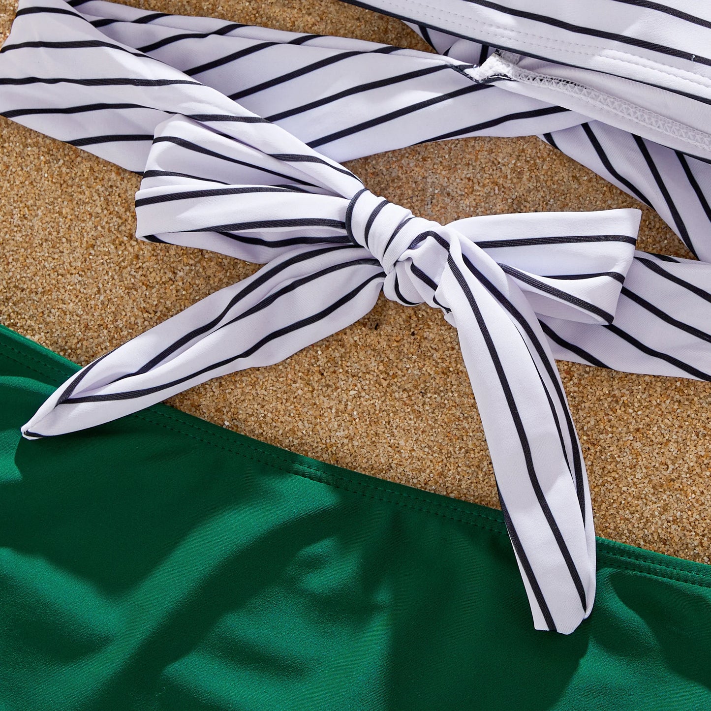Family playing in sand, all dressed in their matching green striped summer outfits