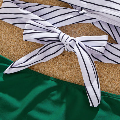 Family playing in sand, all dressed in their matching green striped summer outfits