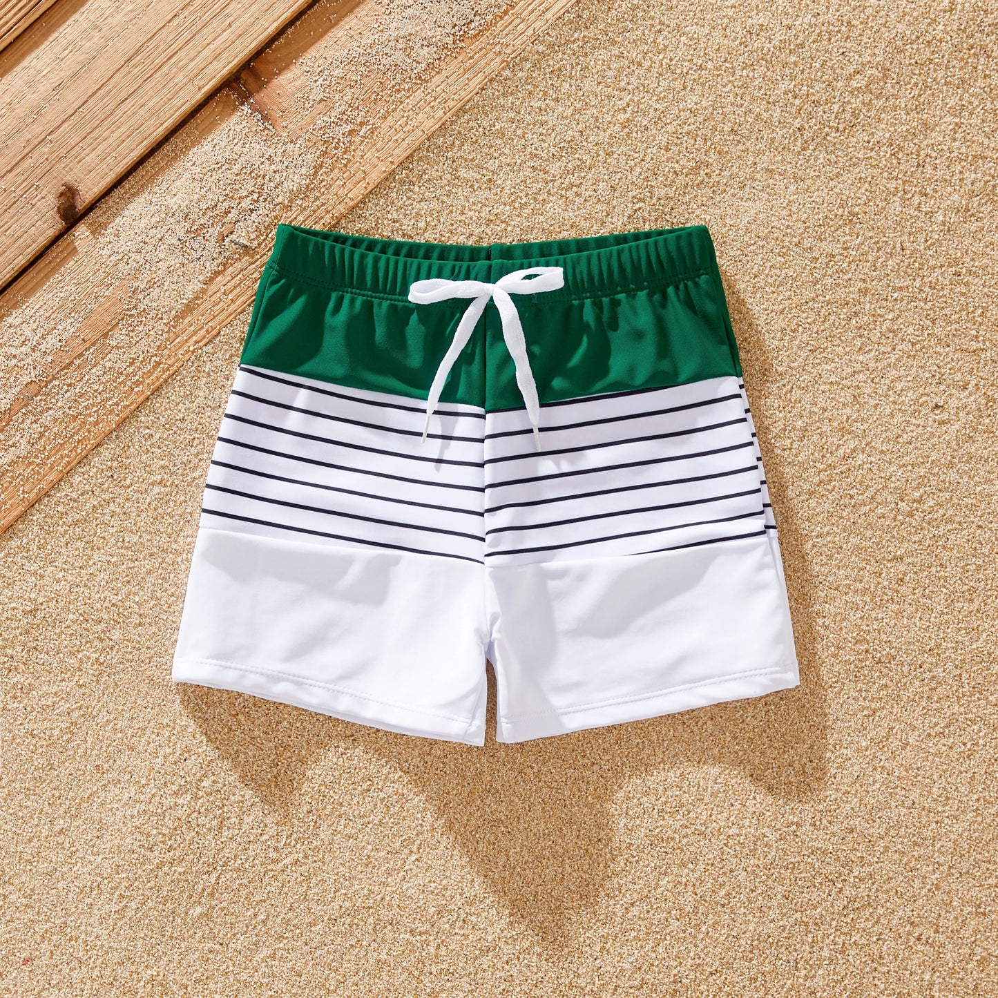 Family in stylish green striped swimsuits enjoying summer holiday by the pool