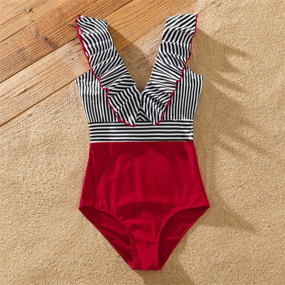 Full shot of family in striped swimsuits, enjoying summer vacation in matching outfits.